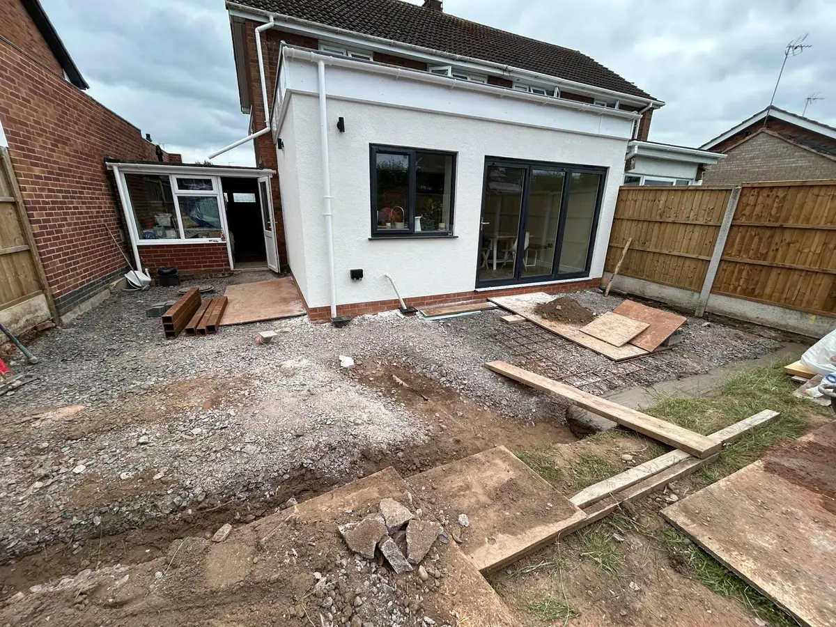 Rendered single-storey rear extension with dark bi-fold doors, before the patio was laid