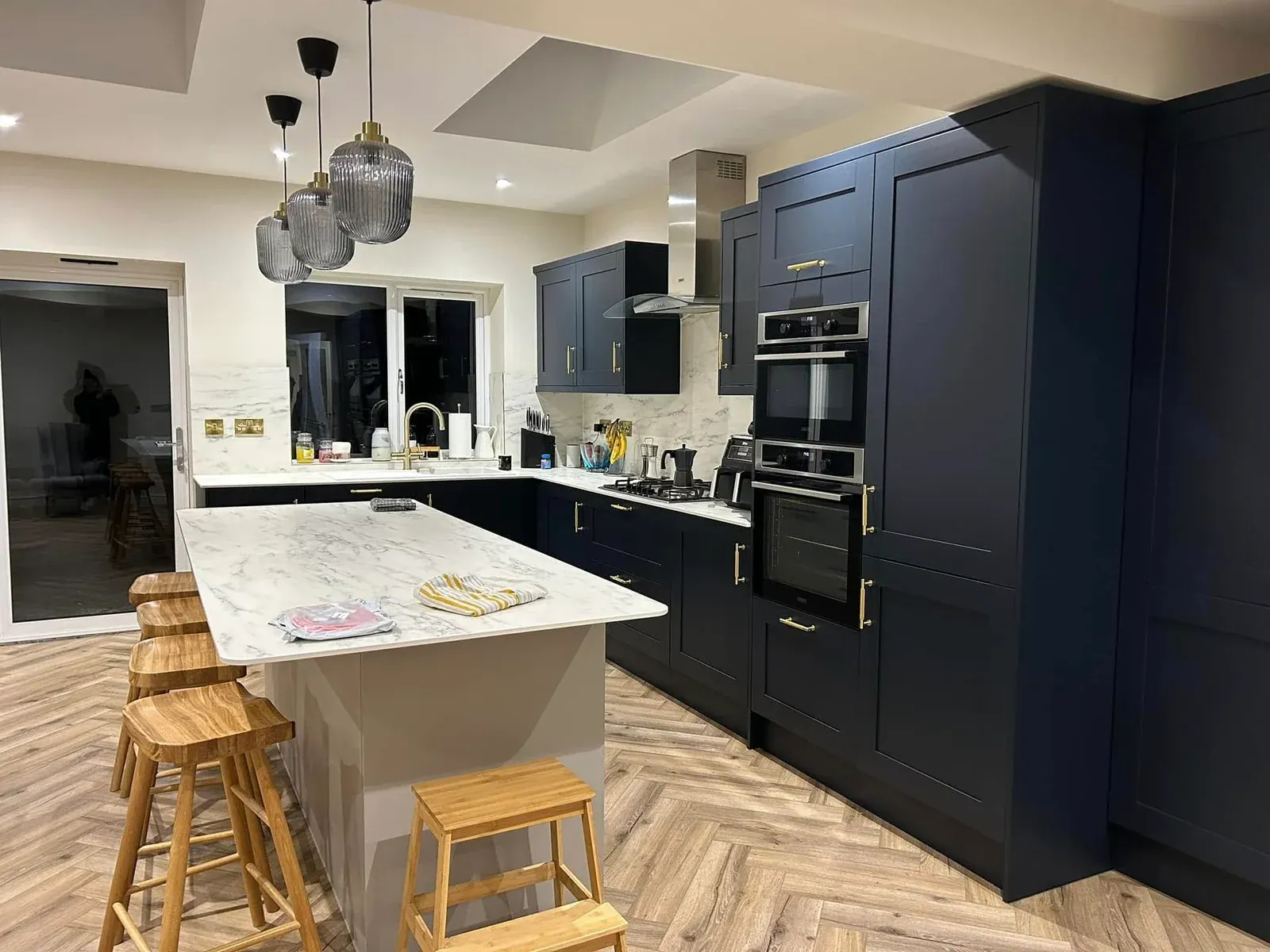 Finished kitchen with navy shaker units, built-in ovens, marble-effect island and roof lights