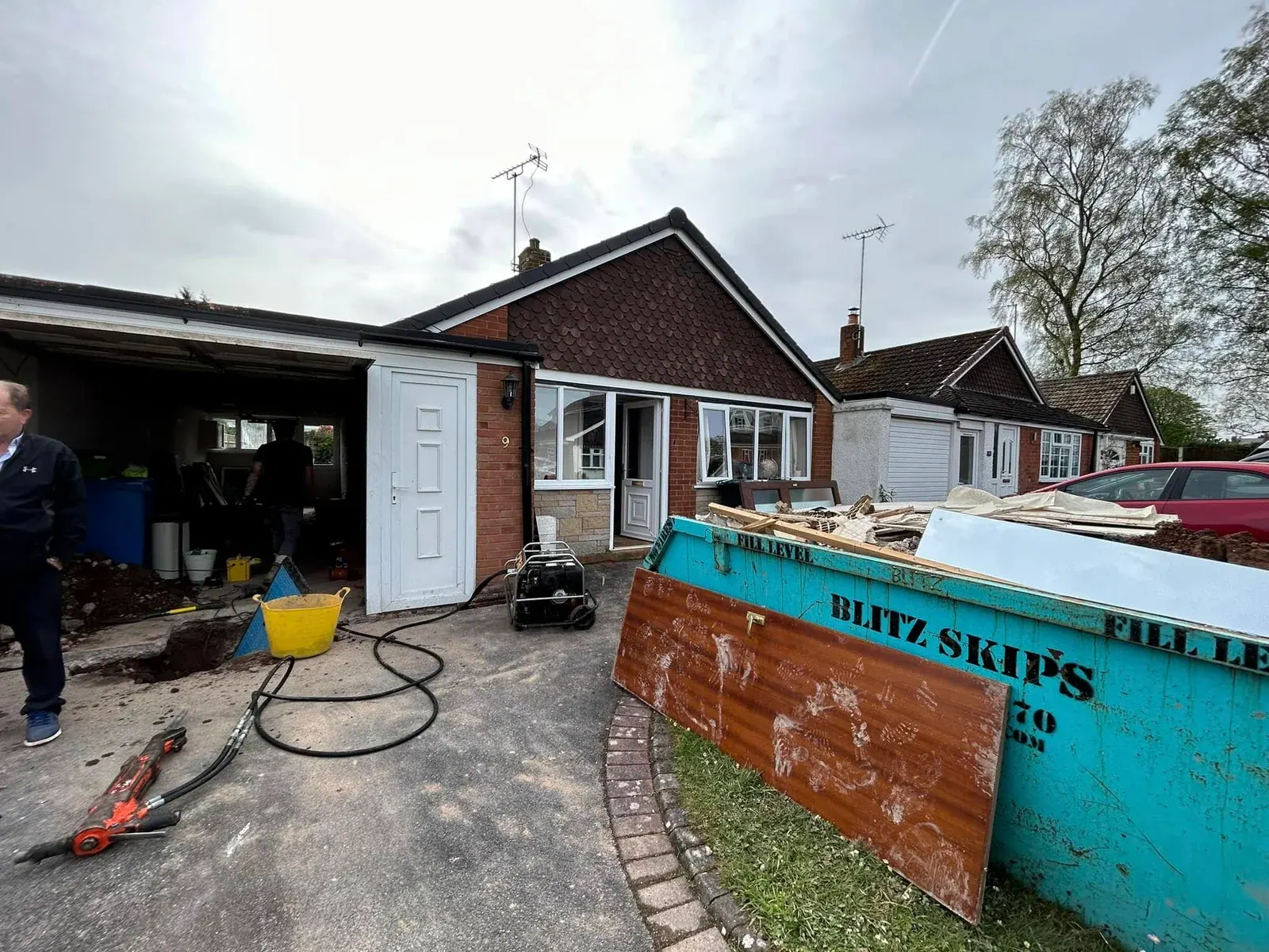 Garage conversion under way at a bungalow, with a skip beside the driveway