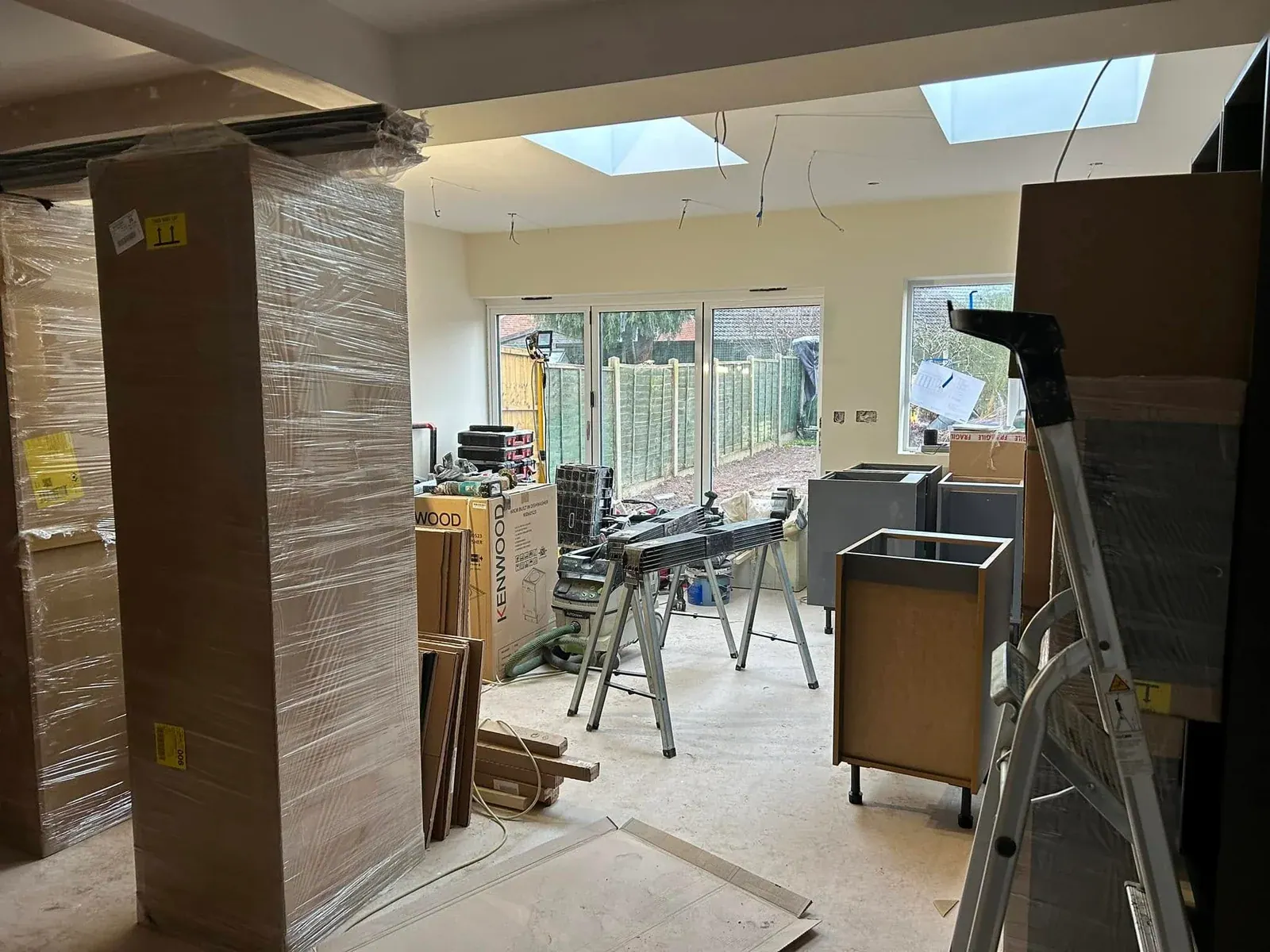 Rear extension interior during fit-out, with roof lights, bi-fold doors and wrapped kitchen units