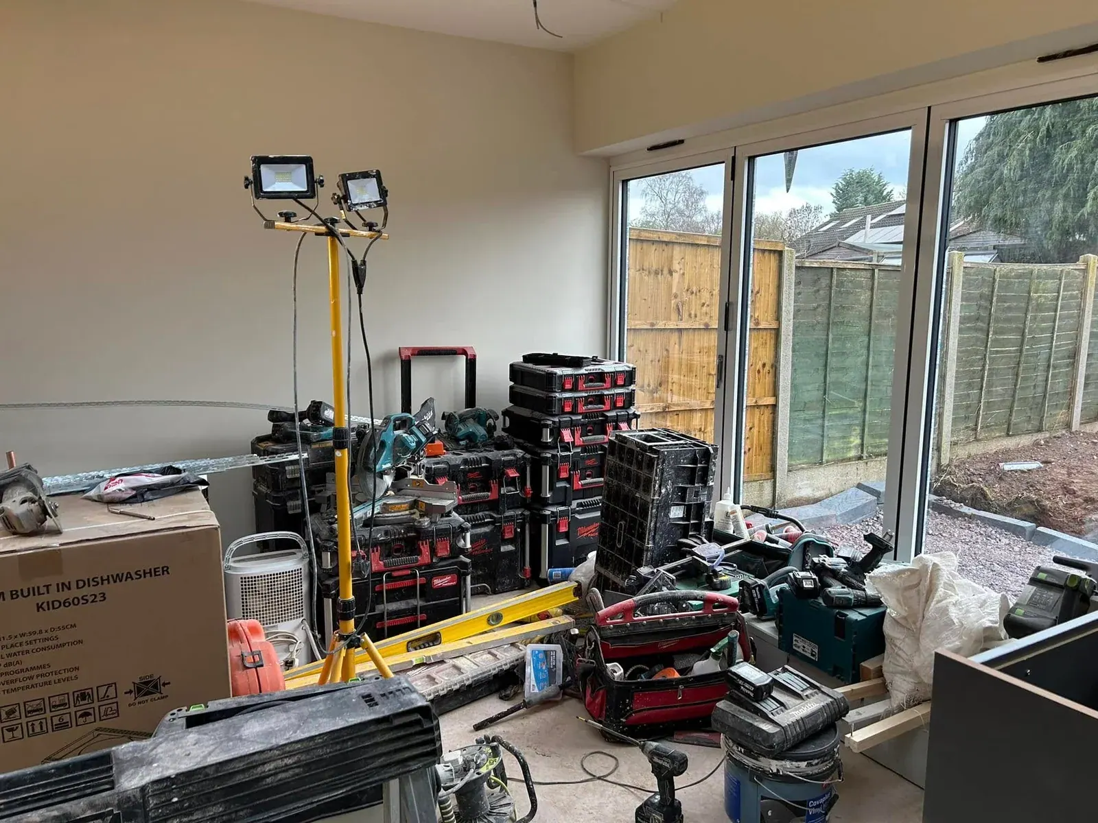 Extension interior with bi-fold doors onto the garden, with tools and equipment during fit-out