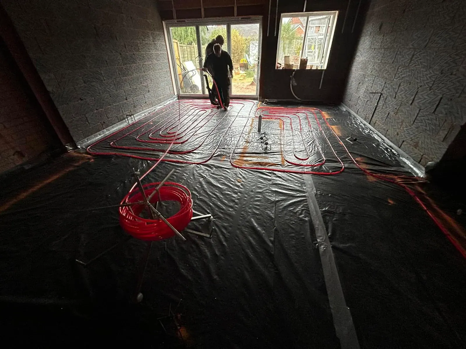 Underfloor heating pipes laid over a membrane inside a blockwork extension shell