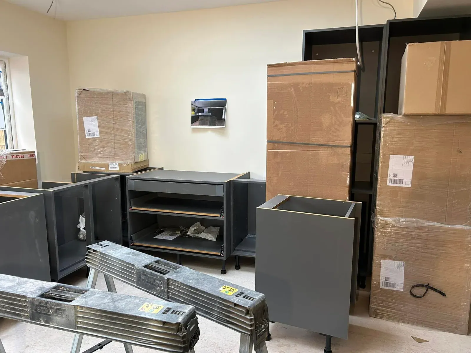 Grey kitchen base units and boxed units waiting to be fitted in a new extension