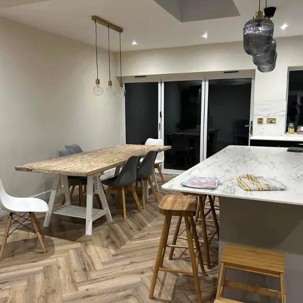 Finished open-plan kitchen diner with herringbone floor, marble-effect island and bi-fold doors