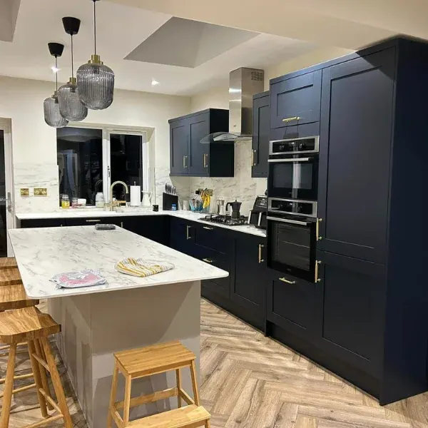 Finished kitchen with navy shaker units, built-in ovens, marble-effect island and roof lights